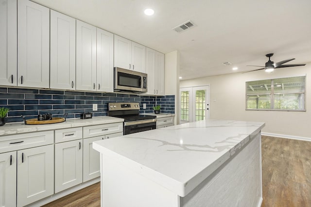 kitchen with a center island, light hardwood / wood-style flooring, decorative backsplash, appliances with stainless steel finishes, and white cabinetry