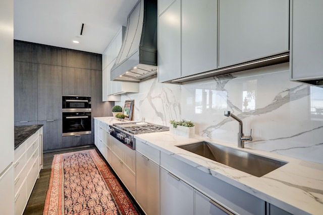 kitchen with premium range hood, light stone counters, stainless steel appliances, and sink