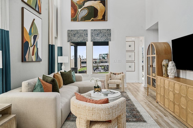 living room featuring light wood-type flooring and a high ceiling