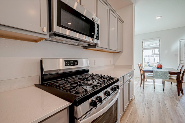 kitchen featuring stainless steel appliances, gray cabinets, and light hardwood / wood-style floors