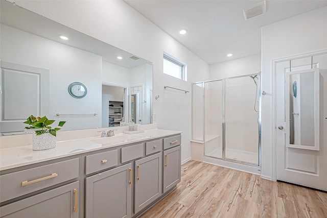 bathroom with hardwood / wood-style flooring, vanity, and a shower with door