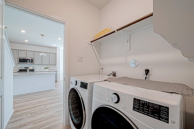 laundry area featuring washer and clothes dryer and light hardwood / wood-style floors