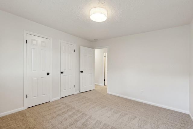 unfurnished bedroom with a textured ceiling and light colored carpet