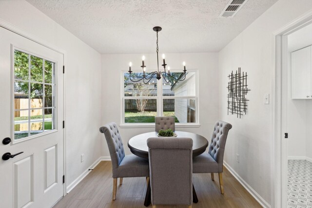 dining room featuring hardwood / wood-style flooring, a textured ceiling, and an inviting chandelier