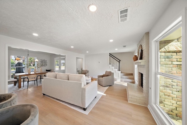 living room with a fireplace, light hardwood / wood-style floors, and a textured ceiling