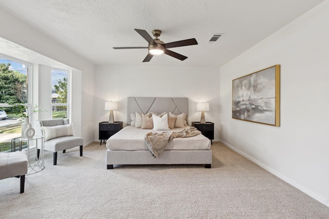 carpeted bedroom with ceiling fan and a textured ceiling