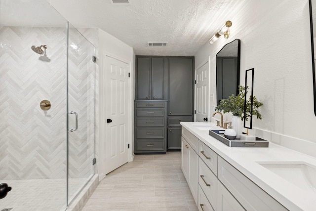 bathroom featuring vanity, a textured ceiling, tile patterned floors, and an enclosed shower