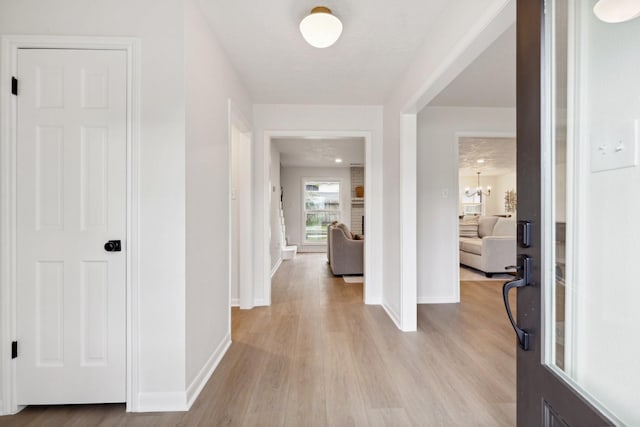 hallway featuring light hardwood / wood-style flooring and a notable chandelier