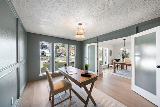 dining area featuring a healthy amount of sunlight, light wood-type flooring, and an inviting chandelier