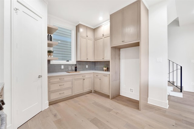 kitchen with light brown cabinets, light wood-type flooring, tasteful backsplash, and sink