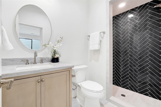 bathroom featuring vanity, toilet, and tiled shower