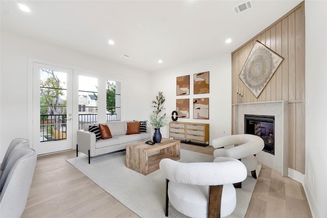 living room with a high end fireplace and light hardwood / wood-style floors