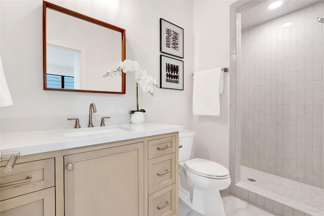 bathroom with vanity, toilet, and tiled shower