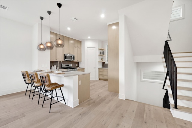 kitchen with hanging light fixtures, stainless steel appliances, light hardwood / wood-style flooring, kitchen peninsula, and a breakfast bar area