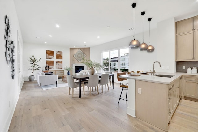 kitchen featuring sink, hanging light fixtures, decorative backsplash, a kitchen bar, and kitchen peninsula