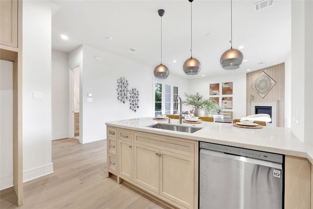 kitchen with sink, hanging light fixtures, stainless steel dishwasher, light stone countertops, and a fireplace