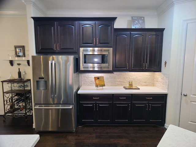 kitchen featuring backsplash, dark hardwood / wood-style floors, ornamental molding, and stainless steel appliances