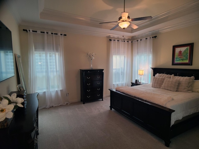 carpeted bedroom with a tray ceiling, ceiling fan, and crown molding