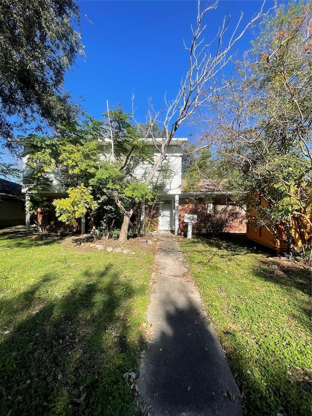 view of property hidden behind natural elements with a front lawn