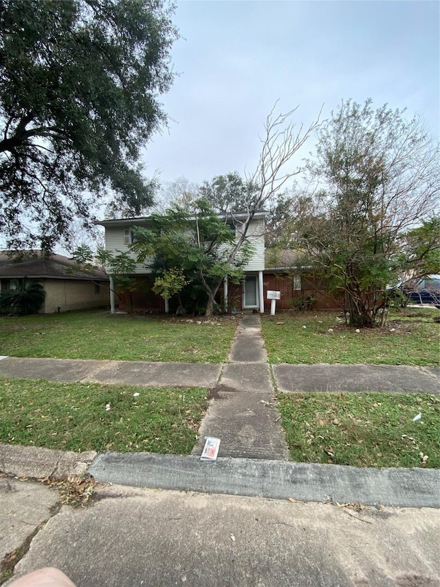 view of property hidden behind natural elements featuring a front yard