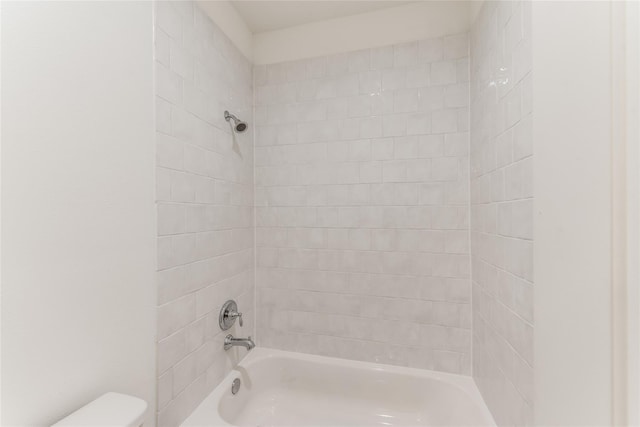 bathroom featuring toilet and tiled shower / bath