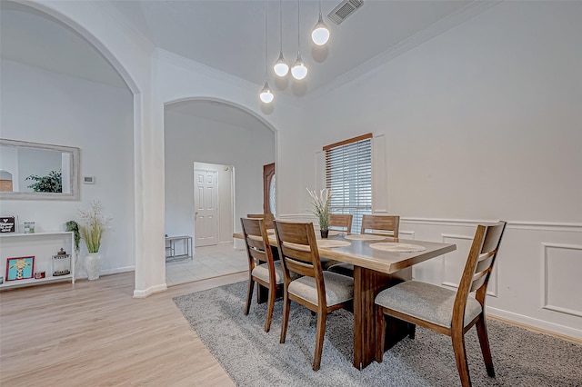 dining room with crown molding and light hardwood / wood-style floors