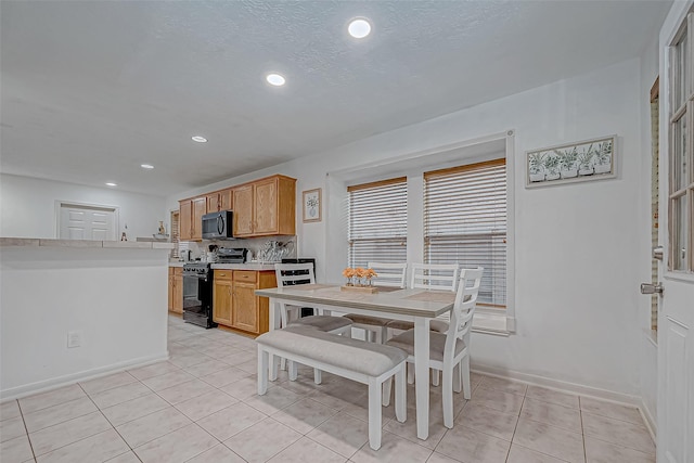 kitchen with backsplash, black stove, and light tile patterned flooring