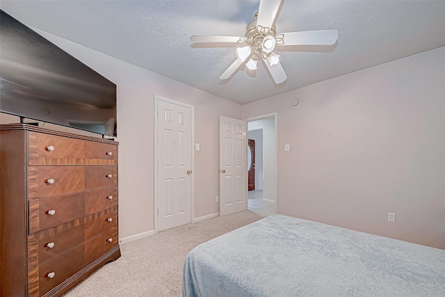 carpeted bedroom with ceiling fan and a textured ceiling