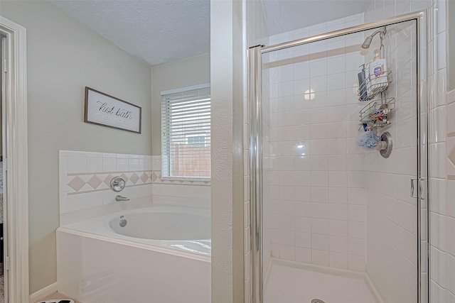 bathroom with plus walk in shower and a textured ceiling