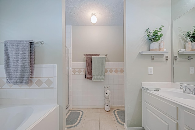 bathroom featuring vanity, tile patterned floors, a washtub, a textured ceiling, and tile walls