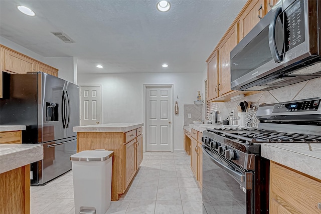 kitchen featuring appliances with stainless steel finishes, a center island, light tile patterned floors, and light brown cabinetry