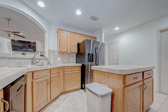 kitchen with tile counters, a center island, decorative backsplash, and stainless steel appliances