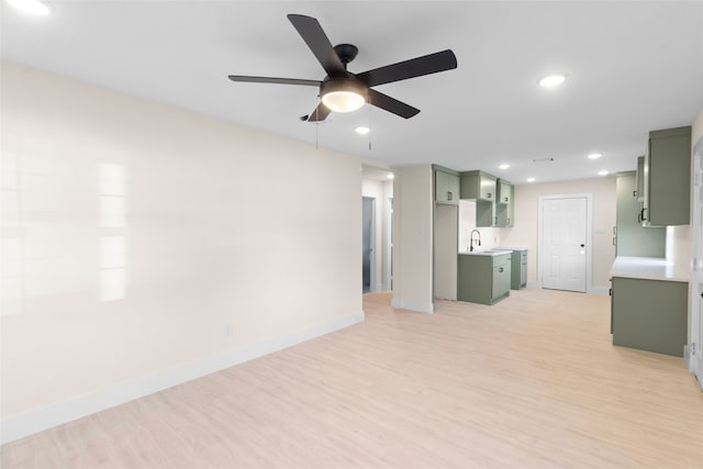 unfurnished living room with ceiling fan, light hardwood / wood-style flooring, and sink