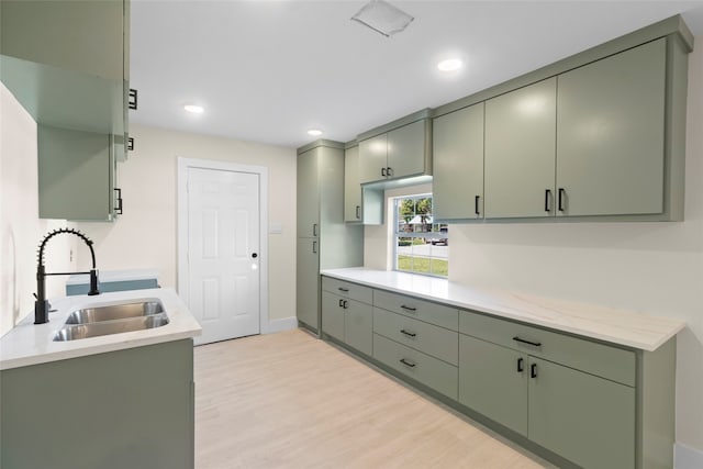 kitchen with green cabinets, sink, and light hardwood / wood-style flooring