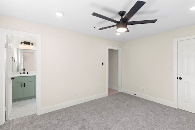 unfurnished bedroom featuring ensuite bath, ceiling fan, sink, and light carpet