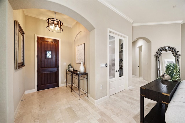 entrance foyer with an inviting chandelier, crown molding, and french doors