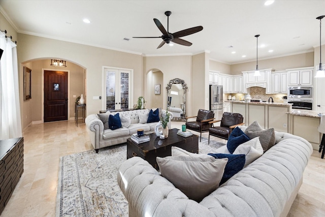 living room with french doors, ceiling fan with notable chandelier, and crown molding