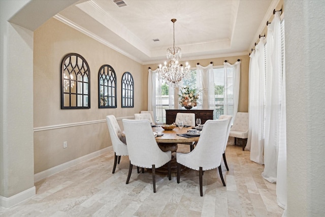 dining space with a tray ceiling, crown molding, and a notable chandelier