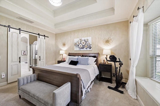 bedroom featuring a barn door, a raised ceiling, light colored carpet, and ensuite bath