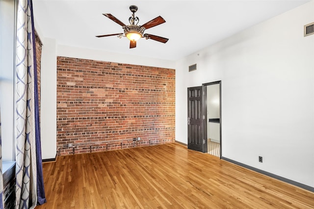 915 Franklin St Unit 3G, Houston, TX 77002 - spare room featuring hardwood / wood-style floors, ceiling fan, and brick wall