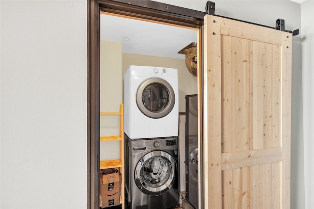 washroom with a barn door and stacked washing maching and dryer