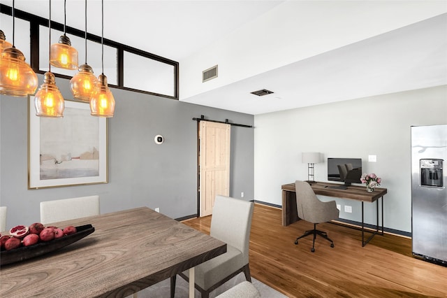 office space with a barn door, hardwood / wood-style floors, and a towering ceiling