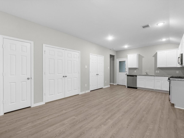 kitchen featuring light wood-type flooring, stainless steel appliances, sink, stone countertops, and white cabinets