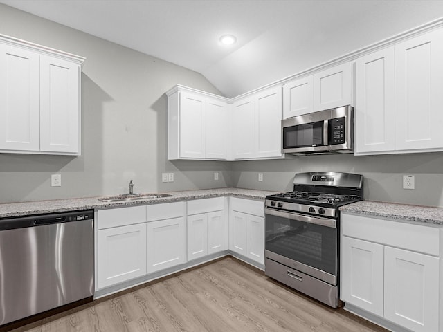 kitchen featuring white cabinetry, sink, stainless steel appliances, light hardwood / wood-style flooring, and lofted ceiling