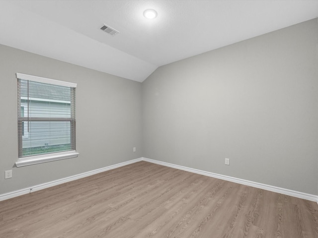 spare room featuring light hardwood / wood-style flooring and lofted ceiling