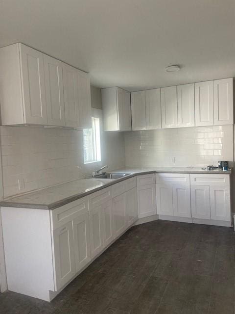 kitchen with dark hardwood / wood-style floors, white cabinetry, sink, and tasteful backsplash