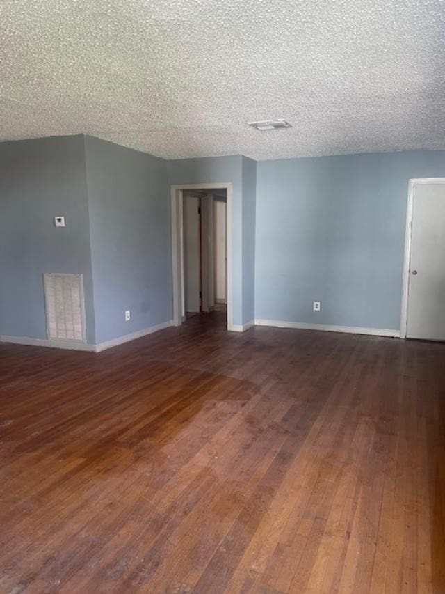 spare room featuring dark hardwood / wood-style floors and a textured ceiling