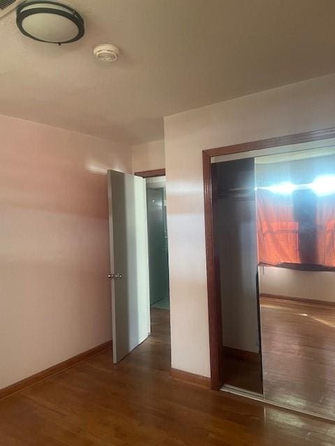 unfurnished bedroom featuring a closet and dark wood-type flooring