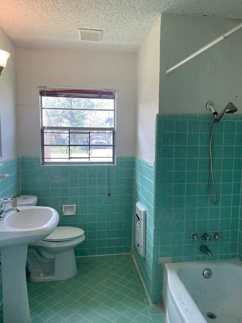 bathroom with wainscoting, tile patterned flooring, tile walls, and a healthy amount of sunlight