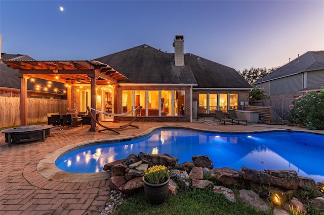 pool at dusk featuring a pergola, a patio, and an outdoor hangout area